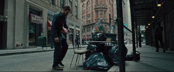 Movie still from “The Super” (2017), directed by Stephan Rick – A man standing next to a pile of garbage on the side of the street; Wide shot, High angle