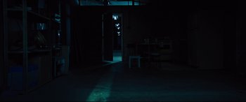 Movie still from “The Super” (2017), directed by Stephan Rick – A dark room with a table and chairs in it; Extreme Wide shot, High angle