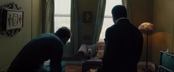 Movie still from “The Super” (2017), directed by Stephan Rick – Two men in a room with a small dog sitting on a chair; Wide shot, Over the shoulder angle