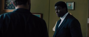 Movie still from “The Super” (2017), directed by Stephan Rick – A man in a suit looking at himself in the mirror; Medium shot, Over the shoulder angle