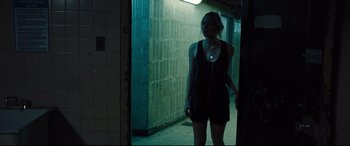 Movie still from “The Super” (2017), directed by Stephan Rick – A woman standing in a dark hallway looking into a mirror; Medium shot, Over the shoulder angle