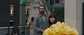 Movie still from “The Super” (2017), directed by Stephan Rick – A man and a woman standing next to each other in front of flowers; Medium shot, Over the shoulder angle