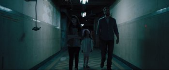 Movie still from “The Super” (2017), directed by Stephan Rick – A man and a woman and a little girl walking down a hallway; Wide shot, Low angle