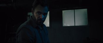 Movie still from “The Super” (2017), directed by Stephan Rick – A man standing in a dark room looking at the camera; Close Up shot, Low angle