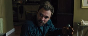 Movie still from “The Super” (2017), directed by Stephan Rick – A man with a goatee is sitting in a room; Close Up shot, Over the shoulder angle