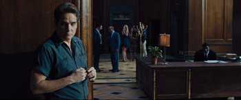Movie still from “The Super” (2017), directed by Stephan Rick – A group of people in suits and ties in a room; Medium shot, Over the shoulder angle