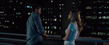 Movie still from “The Super” (2017), directed by Stephan Rick – A man and a woman standing next to each other on a balcony; Medium shot, Over the shoulder angle