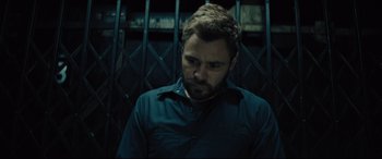 Movie still from “The Super” (2017), directed by Stephan Rick – A man with a beard is standing in front of a metal fence; Close Up shot, Low angle