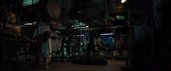 Movie still from “The Super” (2017), directed by Stephan Rick – A man standing next to a guitar case in an industrial setting; Wide shot, High angle