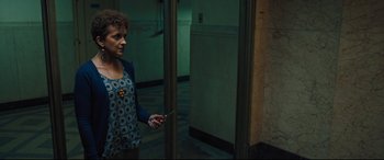 Movie still from “The Super” (2017), directed by Stephan Rick – A woman holding a cell phone standing in front of an open door; Medium shot, High angle