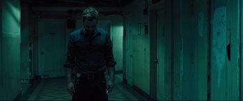 Movie still from “The Super” (2017), directed by Stephan Rick – A man standing in a dark hallway holding a cell phone; Medium shot, Low angle