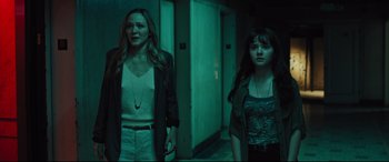 Movie still from “The Super” (2017), directed by Stephan Rick – Two women standing next to each other in a dark room; Medium shot, Low angle