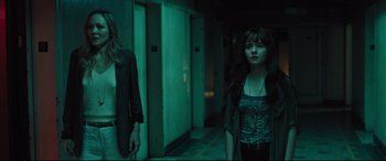 Movie still from “The Super” (2017), directed by Stephan Rick – Two young women standing next to each other in a dark room; Medium shot, Low angle