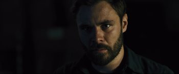 Movie still from “The Super” (2017), directed by Stephan Rick – A man with a goatee stares into the camera; Close Up shot, Over the shoulder angle