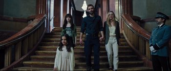 Movie still from “The Super” (2017), directed by Stephan Rick – A man and two women and a little girl standing on some steps; Wide shot, Low angle