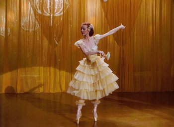 Movie still from “The Tales of Hoffmann” (1951), directed by Michael Powell – A woman in a white dress is dancing on a stage; Wide shot, Low angle