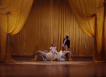 Movie still from “The Tales of Hoffmann” (1951), directed by Michael Powell – A couple of people sitting on top of a couch; Wide shot, Low angle