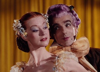 Movie still from “The Tales of Hoffmann” (1951), directed by Michael Powell – A man and a woman are posing for a picture; Close Up shot, Low angle