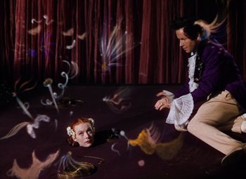 Movie still from “The Tales of Hoffmann” (1951), directed by Michael Powell – A man and a woman are in a room with lights; Wide shot, High angle