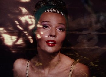 Movie still from “The Tales of Hoffmann” (1951), directed by Michael Powell – A woman with a green head piece and red lipstick; Close Up shot, Low angle