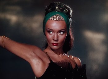 Movie still from “The Tales of Hoffmann” (1951), directed by Michael Powell – A woman in a black dress and a green headpiece; Close Up shot, Low angle