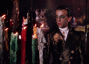 Movie still from “The Tales of Hoffmann” (1951), directed by Michael Powell – A man in a black jacket standing in front of candles; Medium shot, Low angle