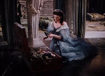 Movie still from “The Tales of Hoffmann” (1951), directed by Michael Powell – A woman in a blue dress looking at a bird; Medium shot, High angle