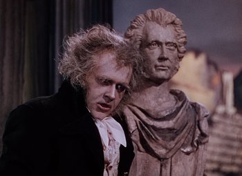Movie still from “The Tales of Hoffmann” (1951), directed by Michael Powell – A person near a statue of a man; Medium shot, Over the shoulder angle