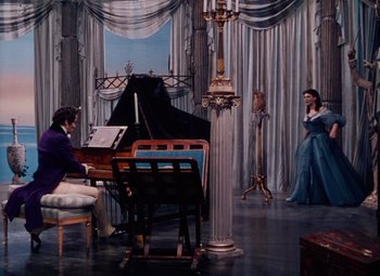 Movie still from “The Tales of Hoffmann” (1951), directed by Michael Powell – A painting of a man and a woman playing piano in front of a grand piano; Wide shot, High angle