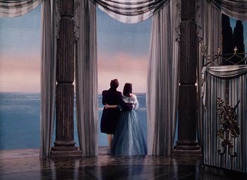 Movie still from “The Tales of Hoffmann” (1951), directed by Michael Powell – Two people are standing in front of a window; Wide shot, High angle