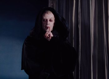 Movie still from “The Tales of Hoffmann” (1951), directed by Michael Powell – A man dressed in black and wearing a black robe; Medium shot, Low angle