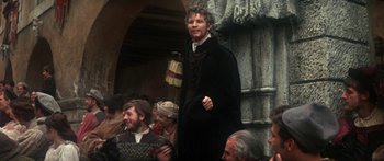 Movie still from “The Taming of The Shrew” (1967), directed by Franco Zeffirelli – A man standing in front of a group of people; Medium shot, Over the shoulder angle