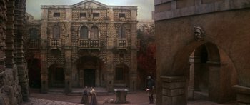 Movie still from “The Taming of The Shrew” (1967), directed by Franco Zeffirelli – Two men and a woman standing in front of an old building; Extreme Wide shot, Low angle