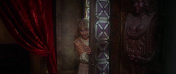 Movie still from “The Taming of The Shrew” (1967), directed by Franco Zeffirelli – A young woman standing next to a stained - glass window; Medium shot, High angle