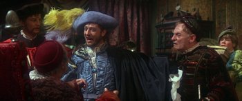 Movie still from “The Taming of The Shrew” (1967), directed by Franco Zeffirelli – A man wearing a blue hat and a black cape; Medium shot, Over the shoulder angle