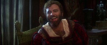 Movie still from “The Taming of The Shrew” (1967), directed by Franco Zeffirelli – A man with a beard is smiling for the camera; Close Up shot, Over the shoulder angle