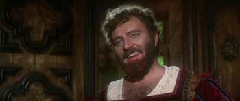 Movie still from “The Taming of The Shrew” (1967), directed by Franco Zeffirelli – A man with a beard is smiling for the camera; Close Up shot, Over the shoulder angle
