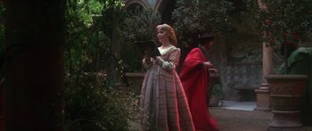 Movie still from “The Taming of The Shrew” (1967), directed by Franco Zeffirelli – A woman dressed in medieval clothing and holding a book; Medium shot, Over the shoulder angle