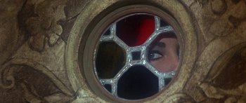 Movie still from “The Taming of The Shrew” (1967), directed by Franco Zeffirelli – A woman looking into a round window with a stained glass design; Extreme Close Up shot, Overhead angle