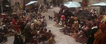 Movie still from “The Taming of The Shrew” (1967), directed by Franco Zeffirelli – A group of people sitting on the ground with an umbrella; Wide shot, High angle