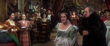Movie still from “The Taming of The Shrew” (1967), directed by Franco Zeffirelli – A woman dressed as a princess in front of a group of people; Medium shot, Over the shoulder angle