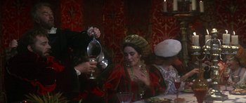 Movie still from “The Taming of The Shrew” (1967), directed by Franco Zeffirelli – A woman pouring a glass of wine into a wine glass; Medium shot, Over the shoulder angle