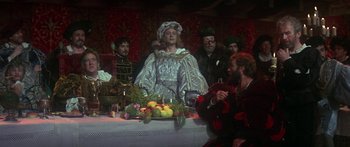 Movie still from “The Taming of The Shrew” (1967), directed by Franco Zeffirelli – A group of people standing around a table; Medium shot, Over the shoulder angle