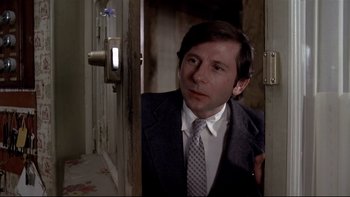 Movie still from “The Tenant” (1976), directed by Roman Polanski – A man wearing a suit and tie standing in a doorway; Close Up shot, Low angle