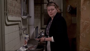 Movie still from “The Tenant” (1976), directed by Roman Polanski – A woman standing in front of a pot in a kitchen; Medium shot, Low angle