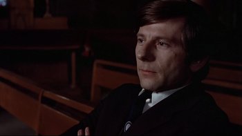Movie still from “The Tenant” (1976), directed by Roman Polanski – A man in a suit and tie sitting in front of a wooden bench; Close Up shot, High angle