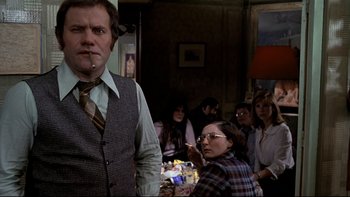 Movie still from “The Tenant” (1976), directed by Roman Polanski – A man and a woman standing in front of a group of people; Medium shot, Over the shoulder angle