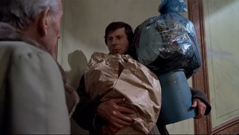 Movie still from “The Tenant” (1976), directed by Roman Polanski – A man is holding a bag of garbage in his hands; Medium shot, Low angle