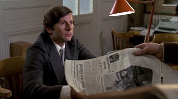 Movie still from “The Tenant” (1976), directed by Roman Polanski – A man sitting at a table reading a newspaper; Medium shot, Over the shoulder angle