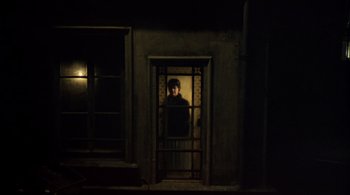 Movie still from “The Tenant” (1976), directed by Roman Polanski – A man standing in a dark room looking out of a window; Wide shot, High angle